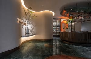 Sophisticated wine bar with a circular counter, potted plants, artwork, and marble flooring
