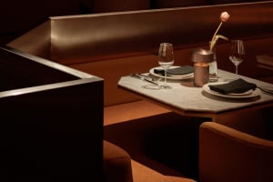 Dining area with a marble table, two chairs, wine glasses, silverware, and a vase of flowers, set in a sophisticated and inviting atmosphere
