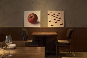 Cozy dining space with a wooden table and two chairs, featuring artwork on the wall and a comfortable seating arrangement