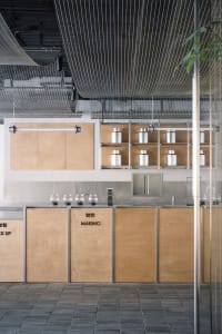 Industrial kitchen with wooden cabinets, metal countertops, and bottles placed on the countertops in various positions