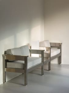 Two single beds in a calm and inviting white room with pillows and no other objects or people