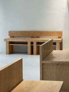 A serene white room with a large oak bench near a wall, creating a calm atmosphere for relaxation