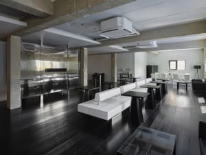 A modern restaurant interior with a large dining area featuring multiple tables and benches, creating a clean and inviting atmosphere