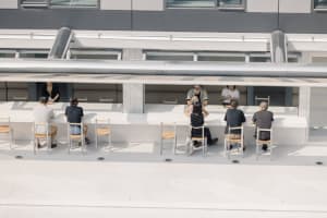 A casual dining area with multiple tables and chairs, featuring a social atmosphere with people gathered to enjoy meals together