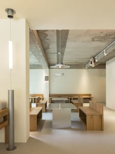 A spacious restaurant interior with wooden tables and benches, surrounded by chairs, creating a warm and inviting atmosphere