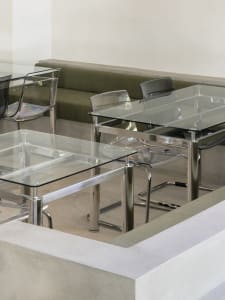 A modern restaurant with multiple dining tables and chairs, creating a comfortable atmosphere for guests, with clean lines and minimalistic decorations, well-lit by natural and artificial light