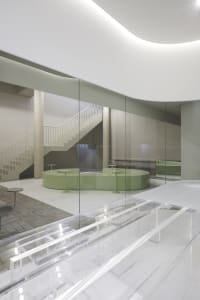 Open modern living space with a glass dining table, four chairs, and a minimalist aesthetic