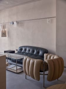 Empty minimalist living room with a couch, two chairs, and a dining table in the background, featuring a clean and minimalistic atmosphere