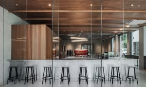 Bright coffee shop interior with glass walls, wooden tables, and black stools, featuring a modern and minimalist design