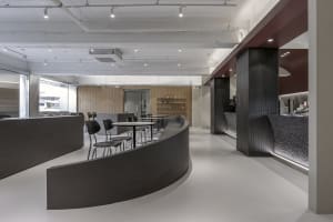 Open restaurant interior with curved design, wood, and metal elements, featuring chairs and dining tables in a modern and inviting atmosphere