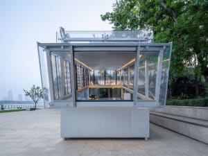 Bright and airy office space with a modern design, featuring a large glass wall, concrete walls, and multiple windows