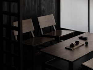 Darkened dining area with a wooden table and four chairs, two bowls placed on the table, creating an intimate and cozy atmosphere