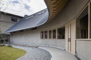A modern house with a curved roof and large window, featuring concrete exterior walls and a well-designed atmosphere