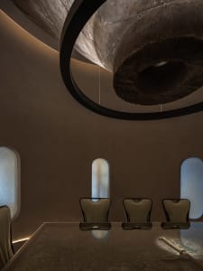 Warm and inviting dining space with a round table, stone walls, and natural light from windows