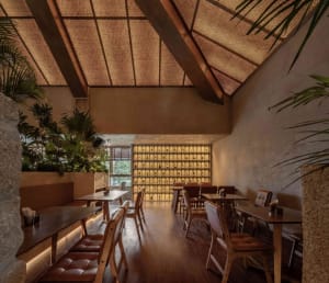 Warm and inviting restaurant interior with wooden floors and walls, multiple dining tables and chairs, and well-lit atmosphere