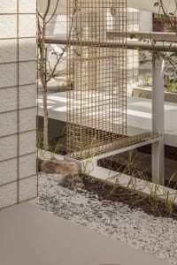 A well-maintained outdoor patio with a white bench and two chairs, surrounded by a small tree and inviting atmosphere