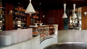 A cozy restaurant interior with a counter displaying food and drinks, wine glasses, and a warm atmosphere