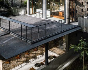 Modern restaurant space with a black roof, scattered chairs, and dining tables, creating a stylish atmosphere for socializing and dining