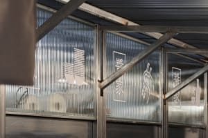 A modern building with a metal roof and traditional Chinese influences, featuring signs and a blend of modern and traditional design elements
