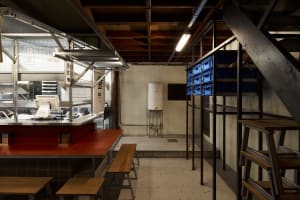 Industrial kitchen with a dining table and chairs, two refrigerators, and a functional atmosphere