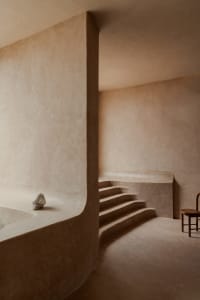 Empty modern room with concrete walls, a staircase, and two chairs, dimly lit