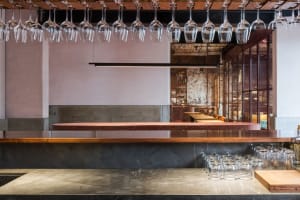 A cozy bar area with a long wooden counter featuring wine glasses and bottles, creating a relaxed atmosphere