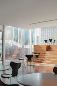 Modern restaurant interior with wooden floors and walls, comfortable seating areas, and ample space for guests