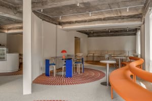A modern cafe with a circular dining area featuring tables and chairs, inviting atmosphere, and clean lines, set against a tiled floor