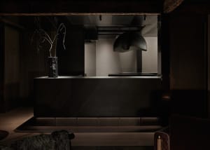 A kitchen with a black countertop, two chairs, a potted plant, and a vase, adding a touch of greenery and decoration