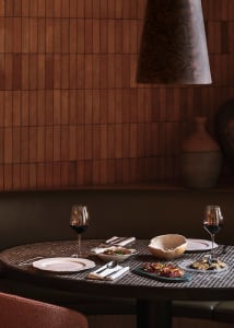 A dining table set with plates, wine glasses, bowls, knives, and a spoon, creating a cozy atmosphere for meals