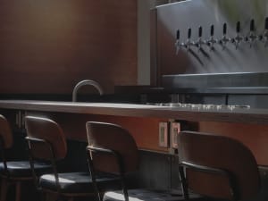 A welcoming bar area with a wooden countertop, multiple beer taps, and comfortable seating for patrons
