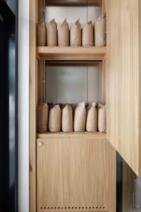 A wooden kitchen cabinet with multiple bags of rice stored inside, showcasing a functional storage solution
