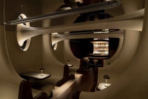 Modern bar area with a long counter and chairs, bottles on display, and a stylish atmosphere