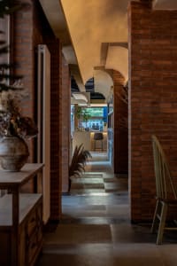 Cozy dining space with a brick wall, wooden floors, and potted plants, featuring a dining table and chairs