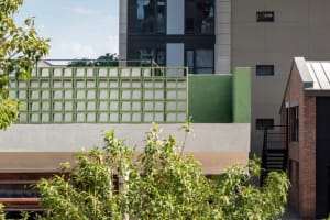 A modern building with multiple levels, a rooftop terrace, and concrete construction, featuring ample natural light through numerous windows