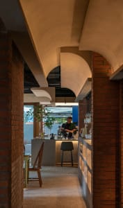 A cozy cafe with a counter, chairs, and potted plants, inviting a relaxed dining atmosphere