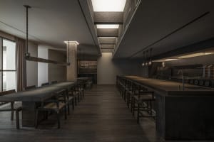 Empty restaurant with wooden floors and tables, chairs placed around the dining area, calm and inviting atmosphere