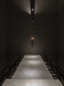 Dimly lit dining area with a wooden table and metal chairs, designed for group gatherings