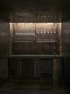 A dark kitchen with a black refrigerator freezer and wine glasses placed throughout, creating a cozy and inviting atmosphere