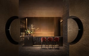 Cozy restaurant interior with red chairs, a dining table, and potted plants, creating a warm and inviting atmosphere
