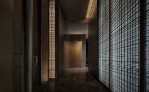 Dimly lit hallway with marble flooring and walls, featuring two doors and a modern luxurious atmosphere
