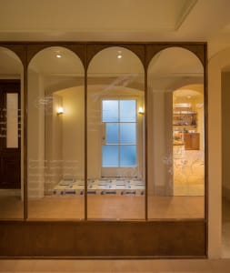 Bathroom interior with wooden walls, two windows, and toiletries on a shelf