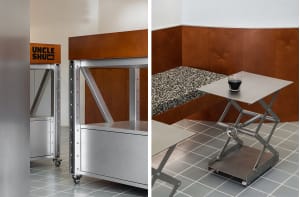 A well-furnished room with a dining area featuring a silver table and chairs, and a bedroom area with a bed and couch, both with wooden floors and a warm atmosphere