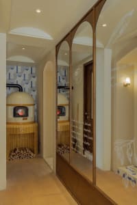 Warm and inviting kitchen space with two wood-burning ovens, tile-adorned walls, and a doorway leading to another part of the building
