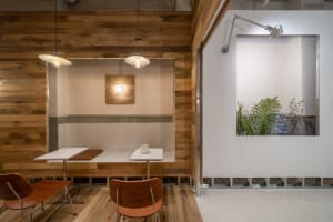 Warm and inviting restaurant interior with wooden walls and floors, two dining tables, chairs, and potted plants