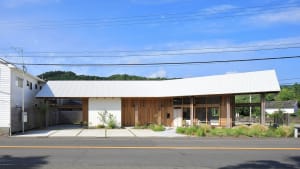 A white house with a prominent wooden design element, featuring several windows that allow natural light to enter the interior spaces, creating a warm and inviting atmosphere
