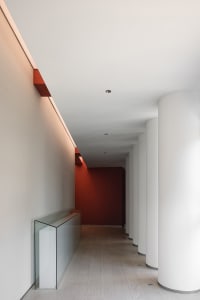 A well-lit hallway with white walls and red accents, featuring two columns and a modern design