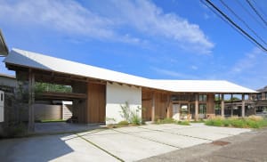 Open modern house with a large wooden structure, a large window, and two outdoor benches