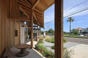 An inviting outdoor patio area with wooden elements, benches, and a dining table, well-lit by natural sunlight