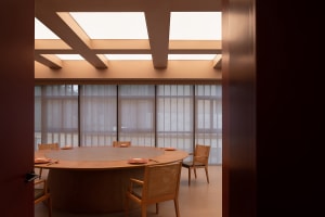 A modern dining space with a large wooden table surrounded by chairs, well-lit and warm atmosphere